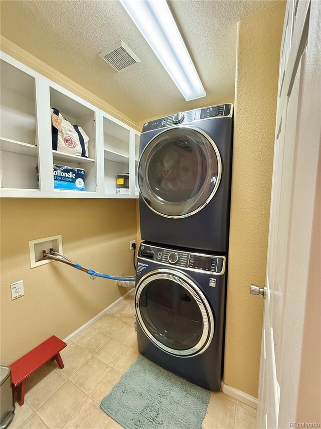 16063 E 106th Ct, Commerce City, CO 80022 - washroom featuring stacked washer / drying machine, tile patterned flooring, baseboards, and a textured ceiling
