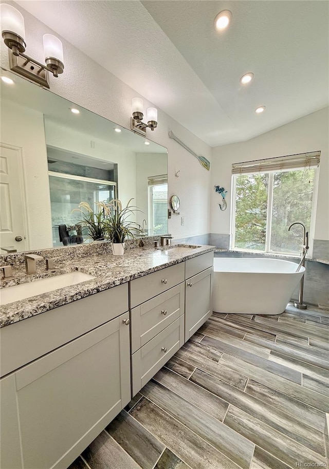 16063 E 106th Ct, Commerce City, CO 80022 - bathroom with double vanity, recessed lighting, wood tiled floors, a freestanding bath, and a stall shower