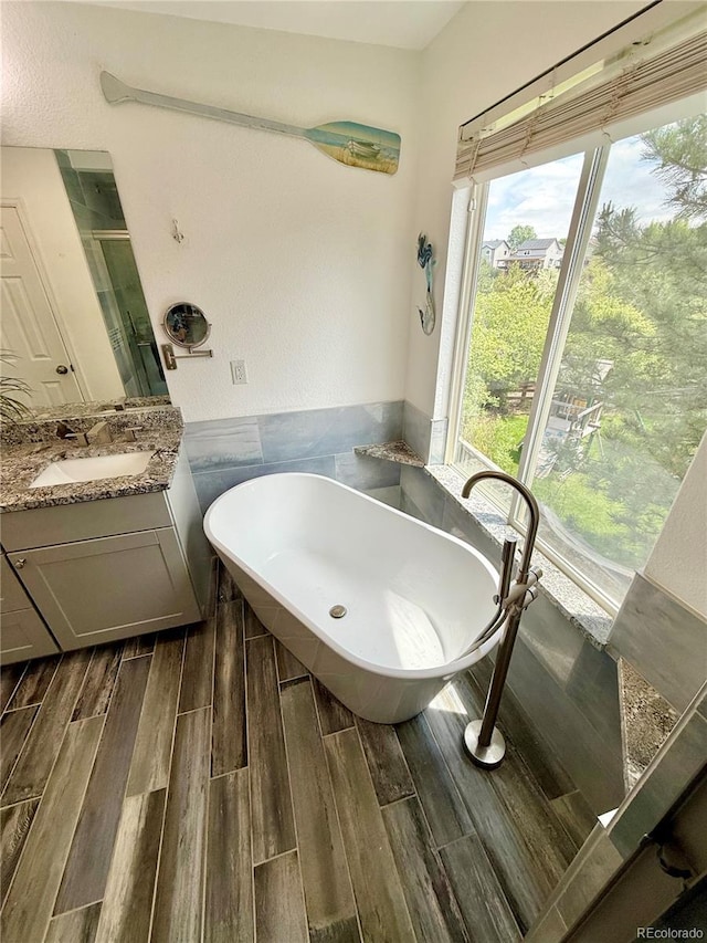 16063 E 106th Ct, Commerce City, CO 80022 - bathroom featuring wood finished floors, a soaking tub, vanity, a shower stall, and tile walls