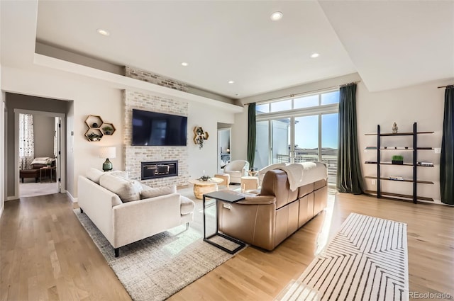 living room with a brick fireplace and light wood-type flooring