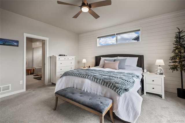 bedroom with light colored carpet, ceiling fan, and wooden walls