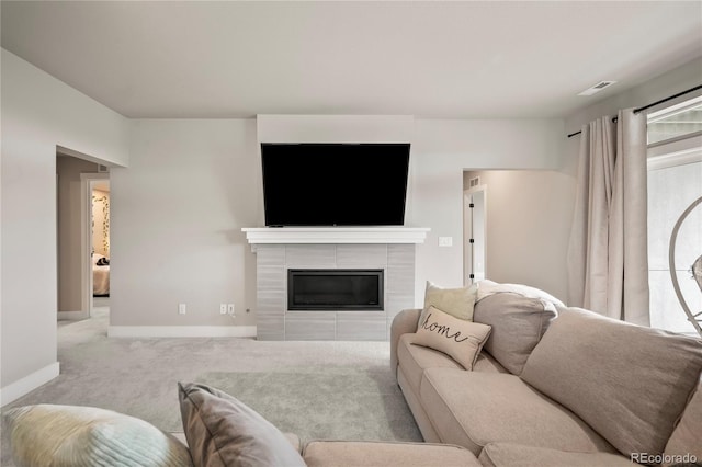 carpeted living room featuring a tiled fireplace