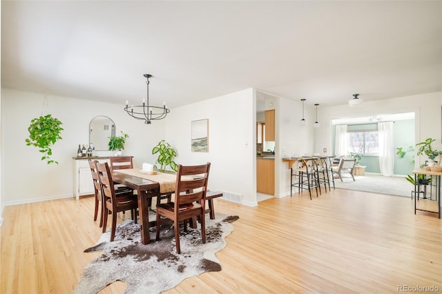 dining area featuring light wood-type flooring, visible vents, and baseboards