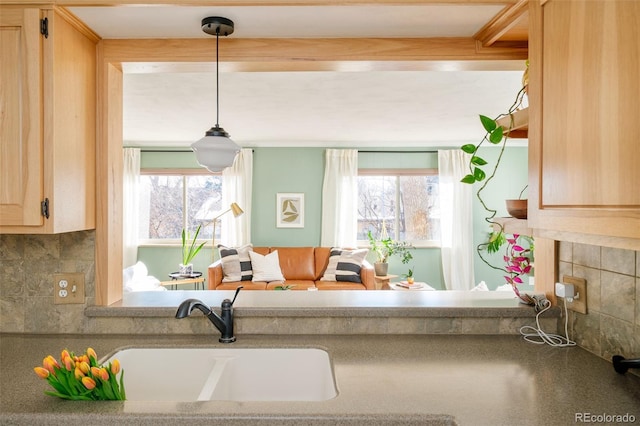 kitchen featuring light brown cabinets, backsplash, a sink, and decorative light fixtures