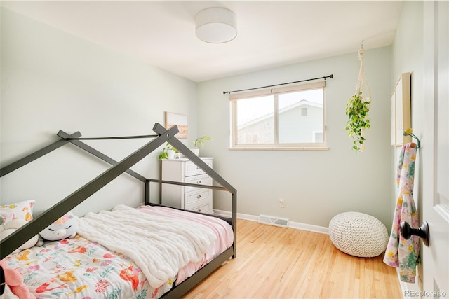 bedroom featuring visible vents, baseboards, and wood finished floors