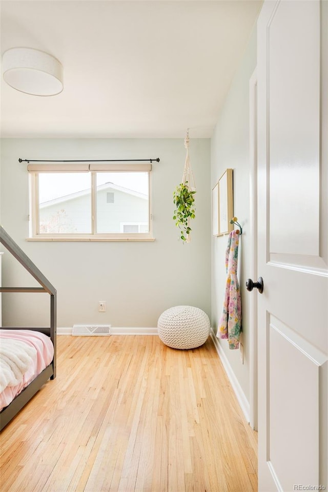 bedroom with baseboards, visible vents, and wood finished floors