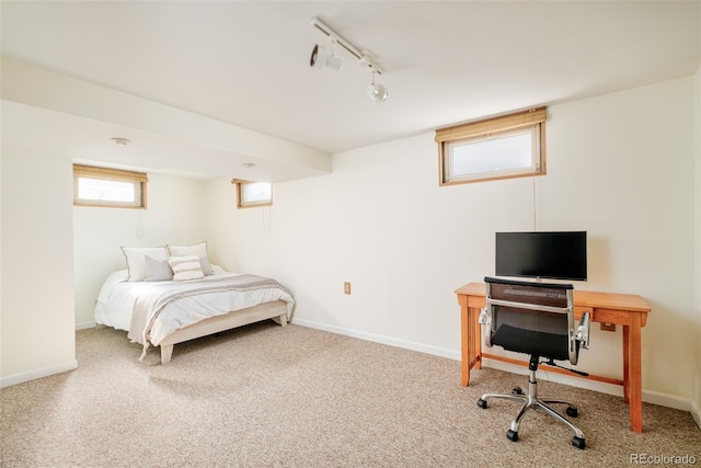 carpeted bedroom featuring rail lighting and baseboards