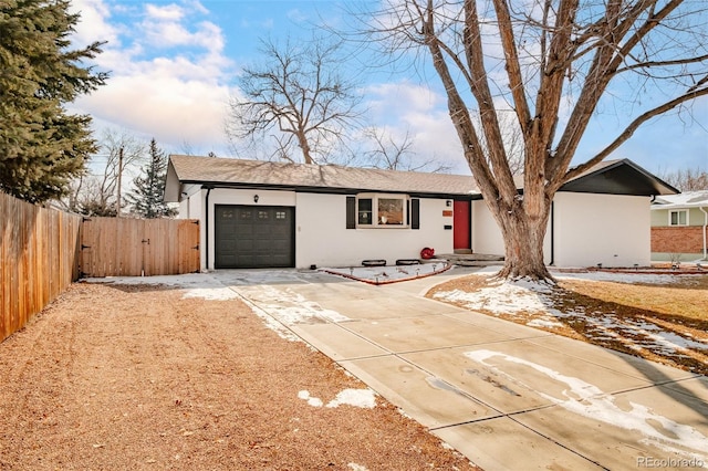 ranch-style house featuring driveway, fence, an attached garage, and stucco siding