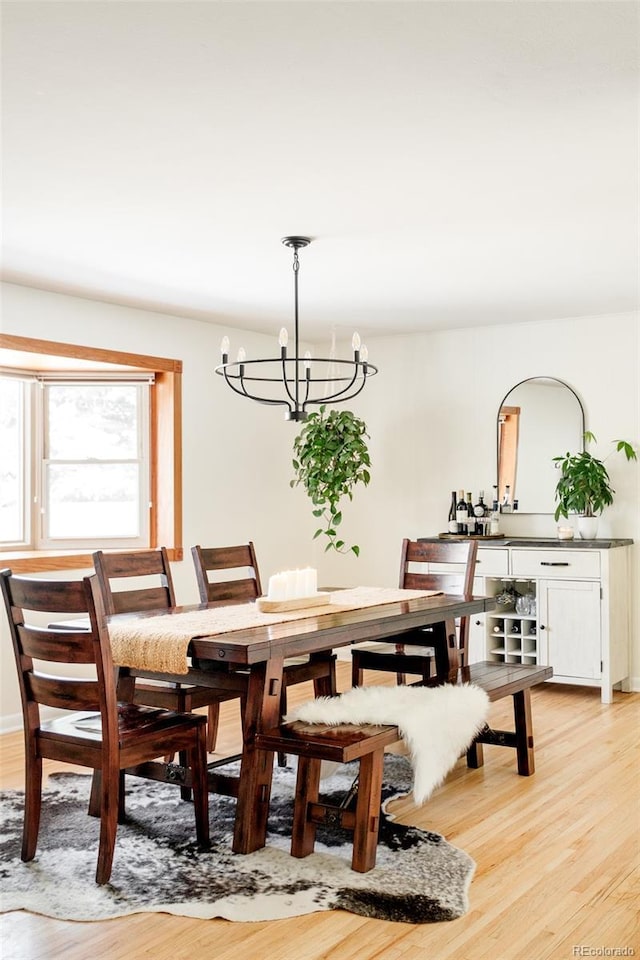 dining space with light wood-type flooring and a notable chandelier