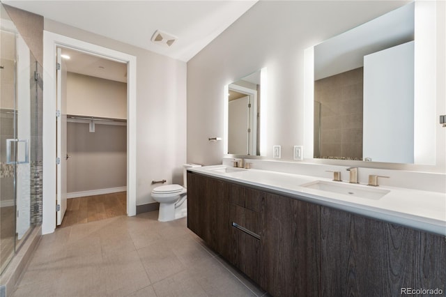 bathroom featuring tile patterned floors, toilet, a shower with door, and vanity