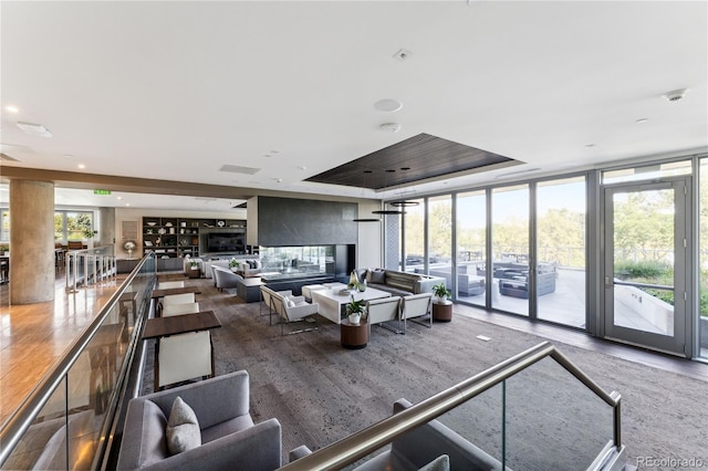 living room featuring hardwood / wood-style floors, a tray ceiling, and floor to ceiling windows