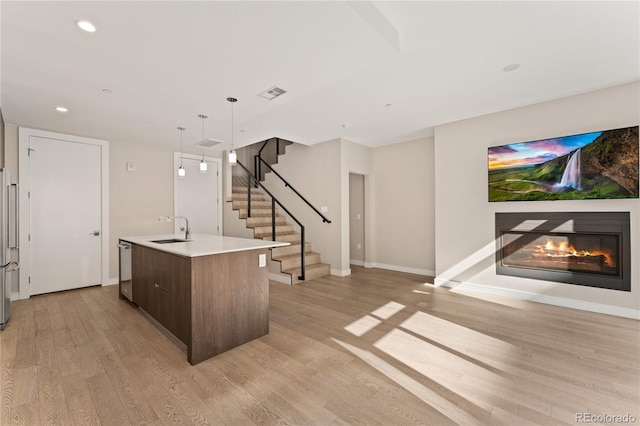 kitchen featuring a center island with sink, stainless steel appliances, light hardwood / wood-style flooring, sink, and dark brown cabinets