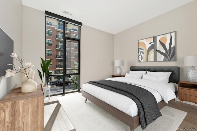 bedroom with access to exterior, expansive windows, and wood-type flooring