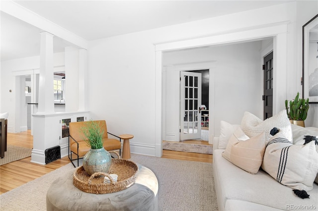 living area with decorative columns, baseboards, and wood finished floors