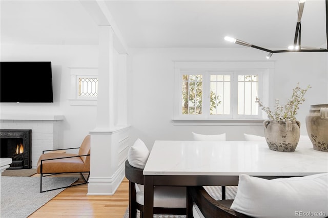 dining space with light wood-type flooring and a brick fireplace