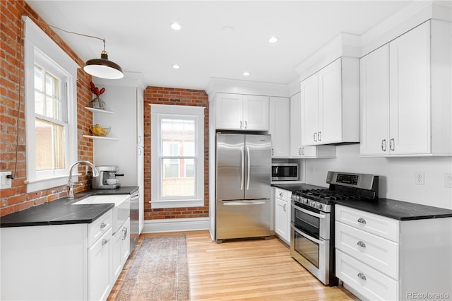 kitchen with open shelves, stainless steel appliances, dark countertops, white cabinetry, and brick wall