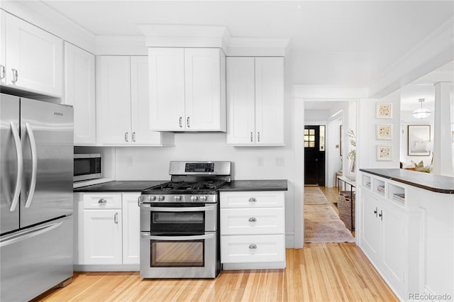 kitchen featuring dark countertops, light wood-type flooring, white cabinets, and stainless steel appliances