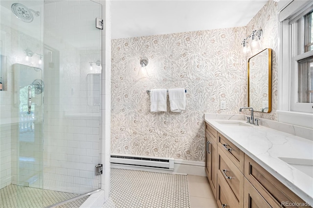 full bath with a baseboard heating unit, a sink, a shower stall, tile patterned flooring, and wallpapered walls