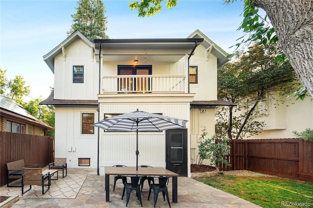 back of property featuring outdoor dining area, a fenced backyard, a patio, and a balcony