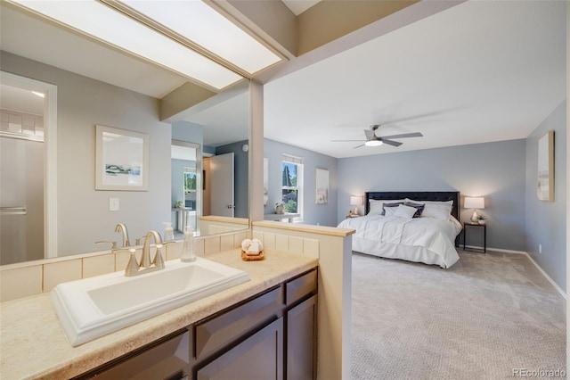bedroom featuring a sink, light colored carpet, baseboards, and a ceiling fan