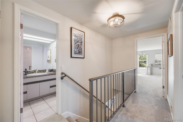 hall featuring an upstairs landing, a sink, and baseboards