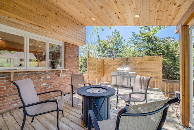 wooden deck featuring an outdoor fire pit, fence, and grilling area