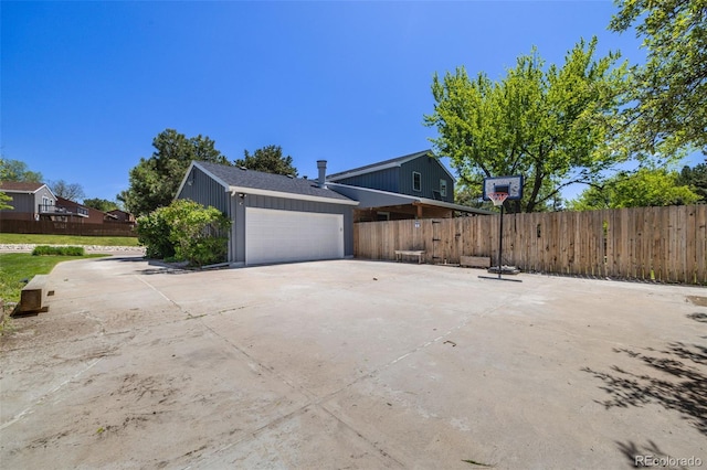 view of side of home with fence, a garage, board and batten siding, and concrete driveway