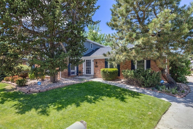 obstructed view of property featuring a front lawn, brick siding, and board and batten siding