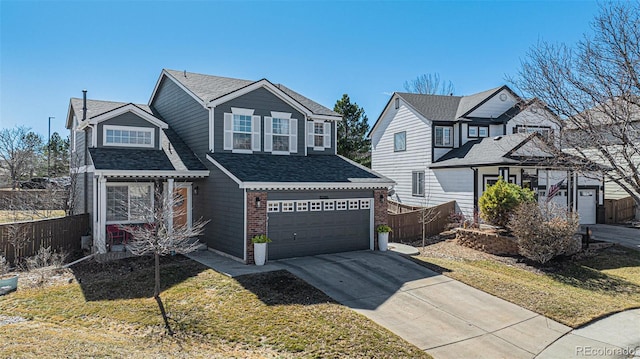 traditional-style home with fence, roof with shingles, an attached garage, concrete driveway, and brick siding