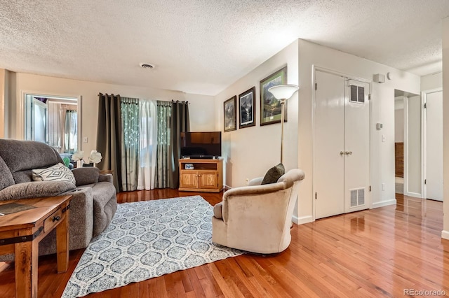 living area with light wood-style floors, visible vents, and a textured ceiling