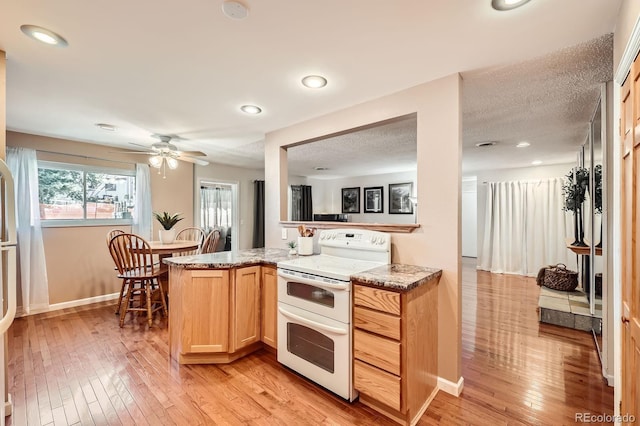 kitchen with a ceiling fan, double oven range, light wood finished floors, light brown cabinetry, and a textured ceiling