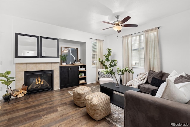 living room with a tiled fireplace, ceiling fan, and dark hardwood / wood-style flooring