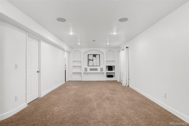 unfurnished living room with built in shelves and carpet