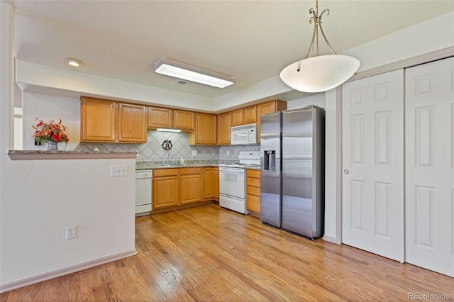 kitchen featuring sink, light hardwood / wood-style flooring, backsplash, pendant lighting, and white appliances