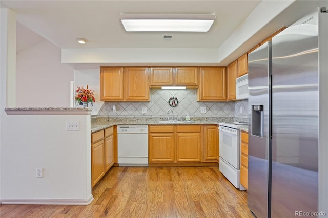 kitchen featuring white appliances, backsplash, sink, light stone countertops, and light hardwood / wood-style floors