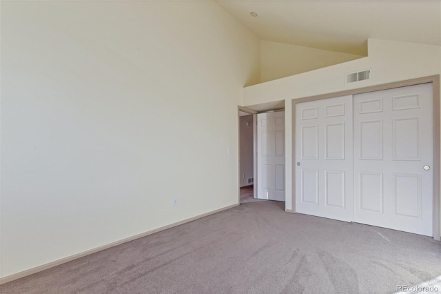 unfurnished bedroom featuring carpet floors, high vaulted ceiling, and a closet