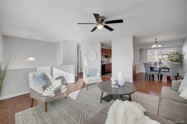 living room featuring ceiling fan with notable chandelier, dark hardwood / wood-style floors, and a textured ceiling