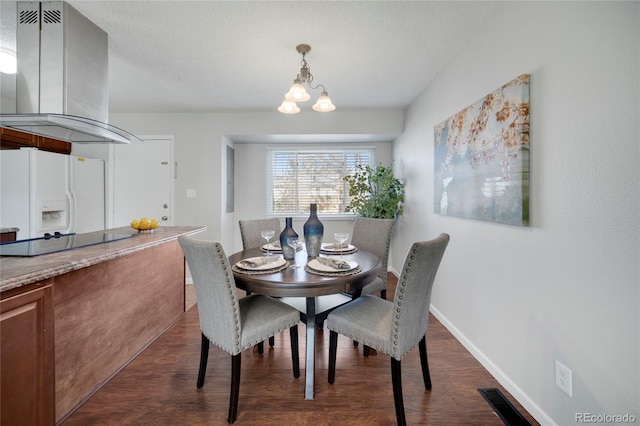 dining space with dark wood-type flooring, a textured ceiling, and a notable chandelier