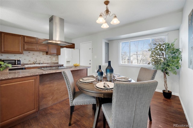 dining room with dark wood-type flooring, sink, and an inviting chandelier