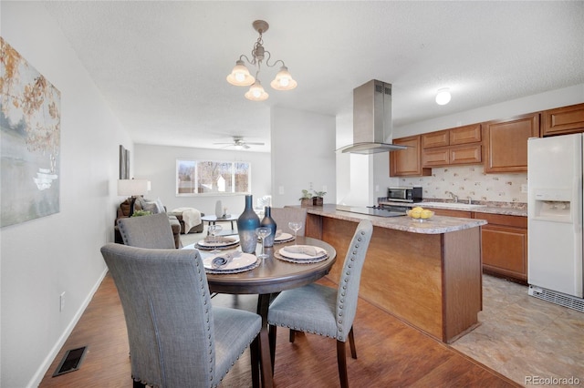 dining space with sink, ceiling fan with notable chandelier, light hardwood / wood-style flooring, and a textured ceiling