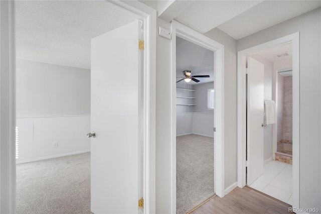 corridor with light carpet and a textured ceiling