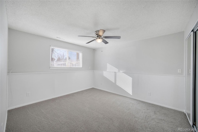 carpeted spare room featuring ceiling fan and a textured ceiling