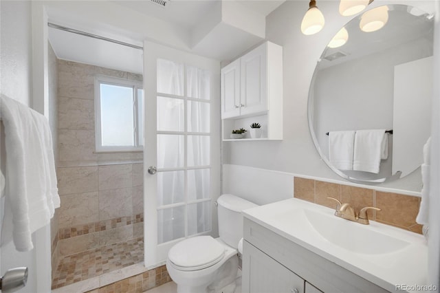 bathroom featuring vanity, tiled shower, backsplash, and toilet