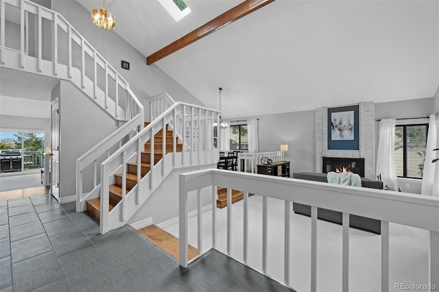 staircase featuring an inviting chandelier, a large fireplace, and a wealth of natural light