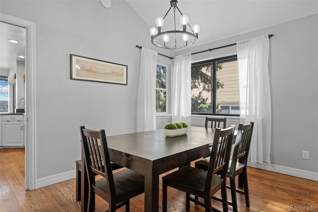 dining area featuring a notable chandelier, lofted ceiling, a healthy amount of sunlight, and light wood finished floors