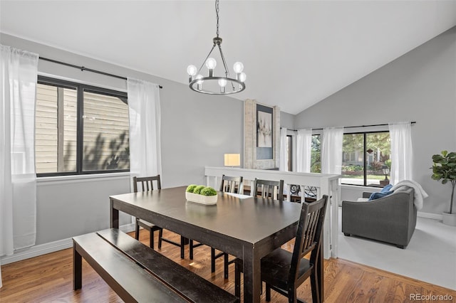 dining space with high vaulted ceiling, wood finished floors, and a notable chandelier