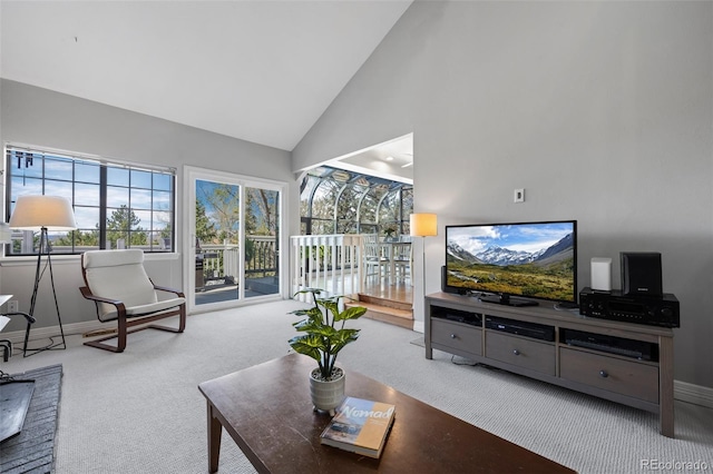 carpeted living area featuring baseboards and high vaulted ceiling