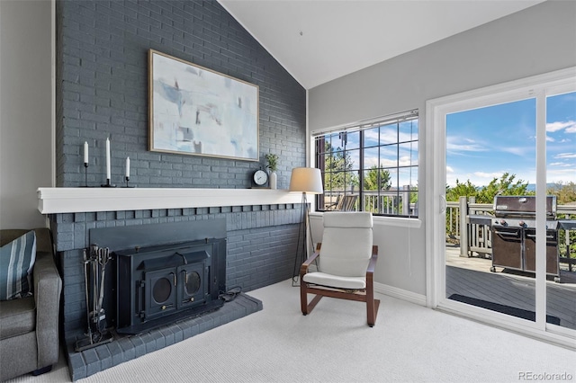 sitting room featuring a wood stove, brick wall, carpet, and lofted ceiling