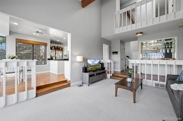 living area with baseboards, ceiling fan, visible vents, and a high ceiling