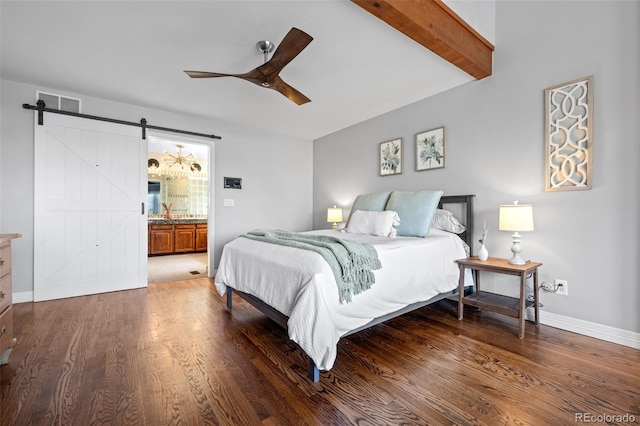 bedroom featuring a barn door, baseboards, wood finished floors, and visible vents